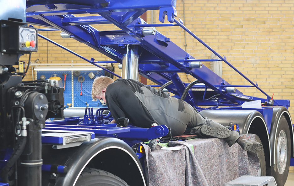 Technician assembling a raised container-hoist frame.